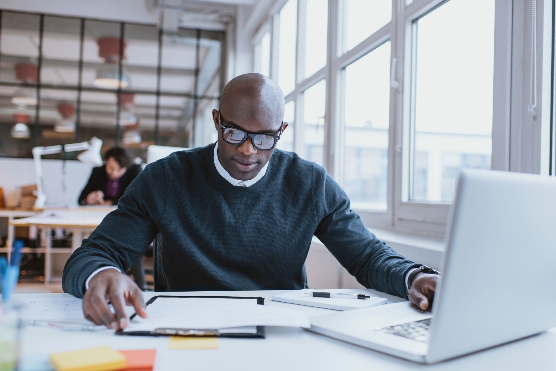 A professional working on a laptop while reviewing project plans